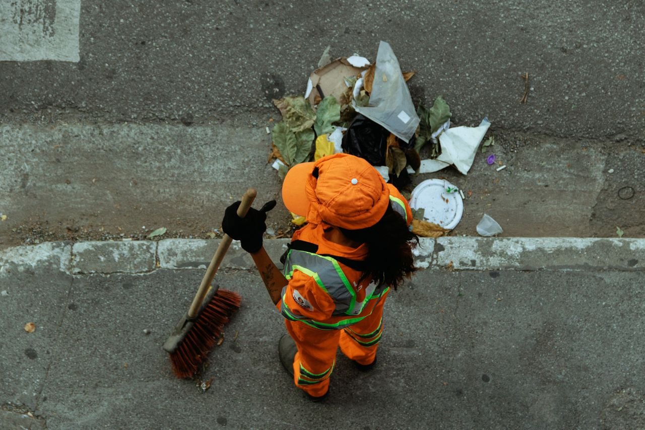 The Art of Drawing Readers In: Your attractive post title goes here Top view of a street cleaner wearing orange uniform sweeping debris on a city sidewalk.